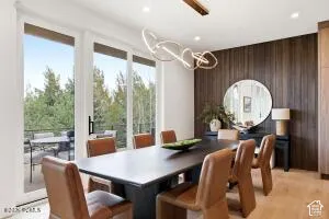 Wood-finish flooring, full-height sliding glass doors, contemporary linear chandelier, and wood-paneled accent wall