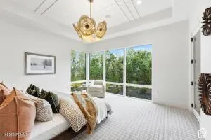 Expansive windows, contemporary ceiling light fixture, tray ceiling, patterned carpeting, and white walls