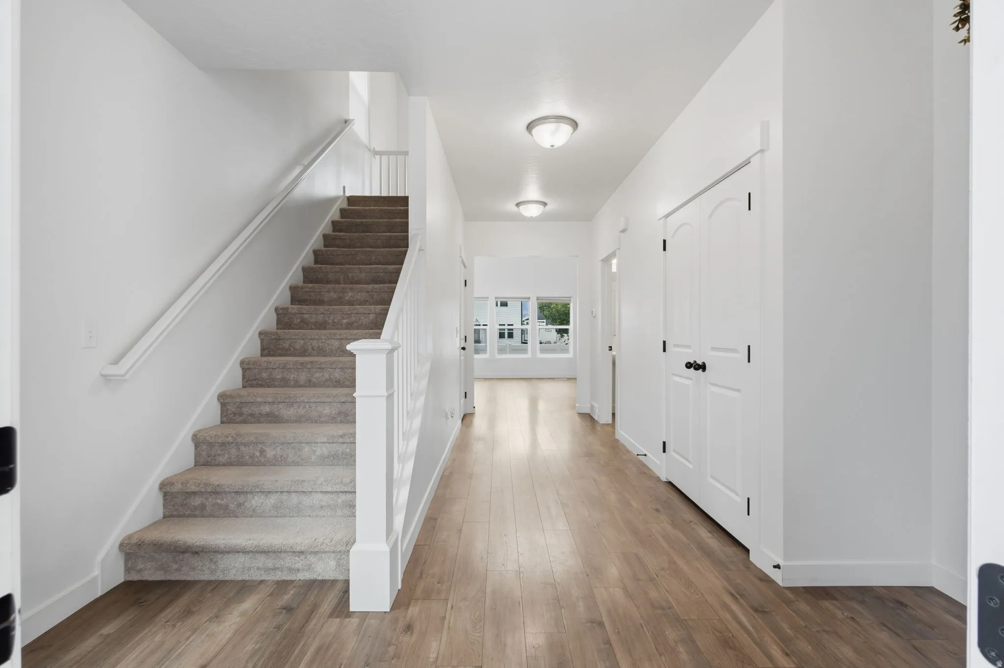 Entryway featuring wood-finish flooring, a carpeted staircase with white balusters, and recessed ceiling lighting