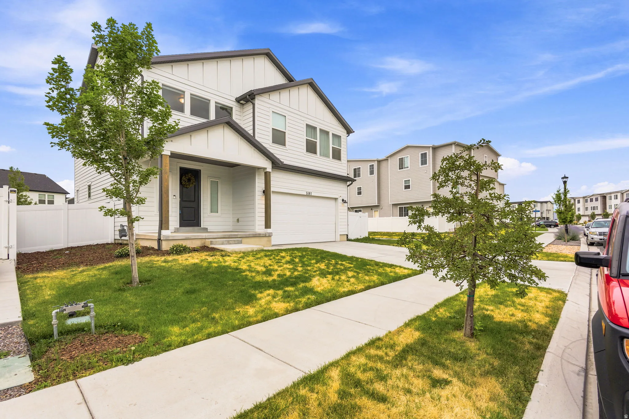 Contemporary two-story residence featuring white vertical siding and dark trim accents