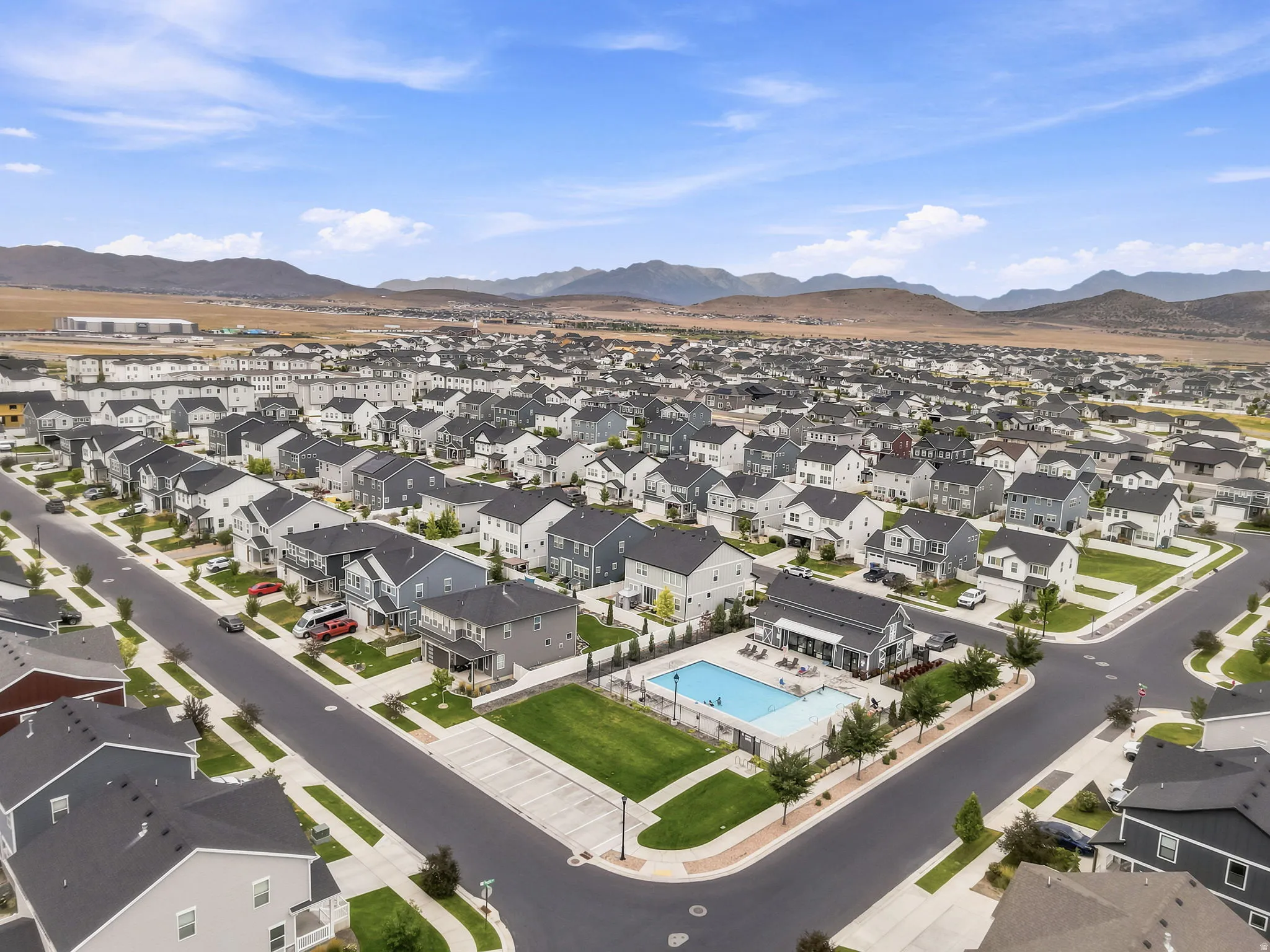 Aerial perspective of a contemporary residential development featuring a community pool and adjacent green space