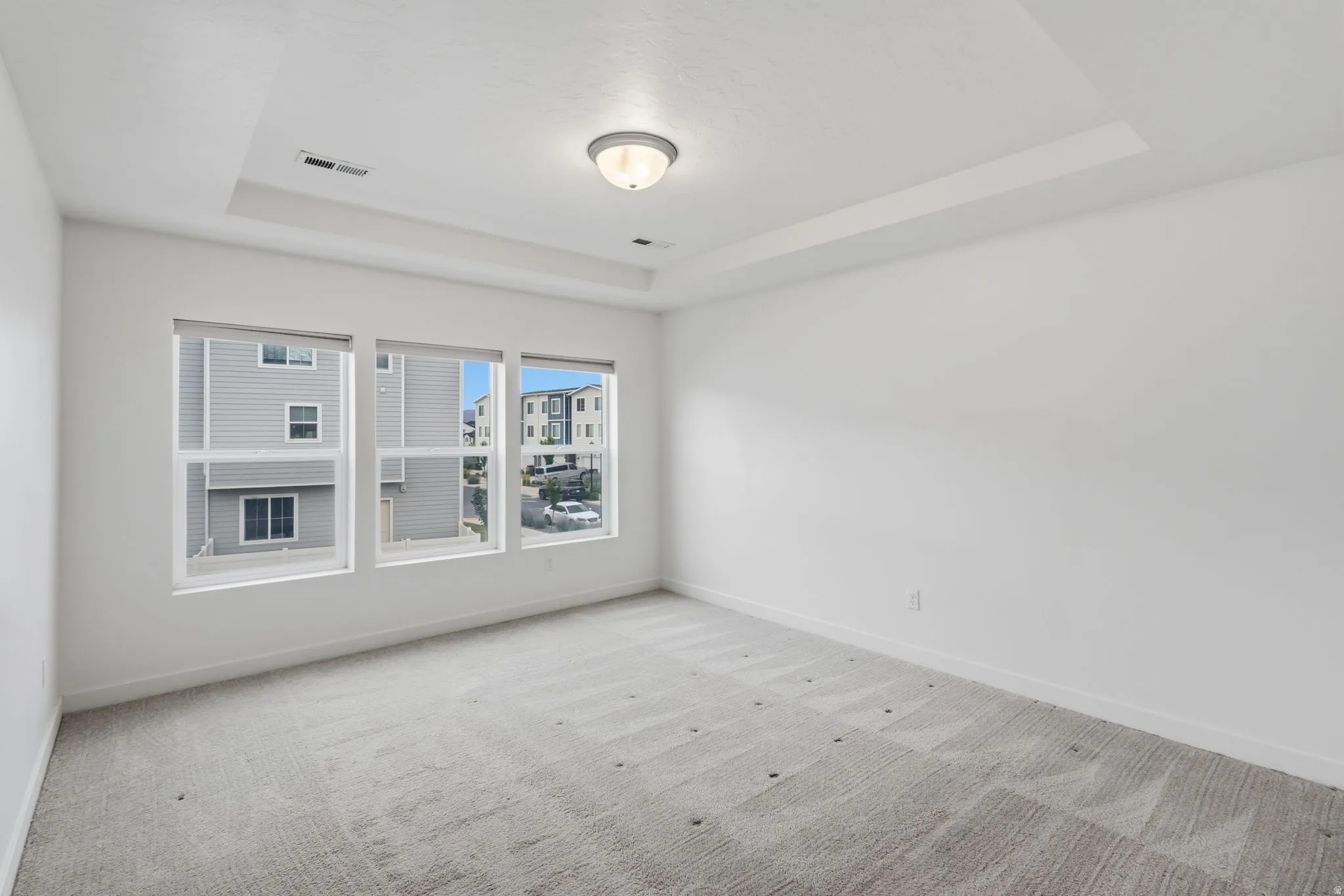 Bright interior space with a tray ceiling, recessed lighting, and a flush mount light fixture