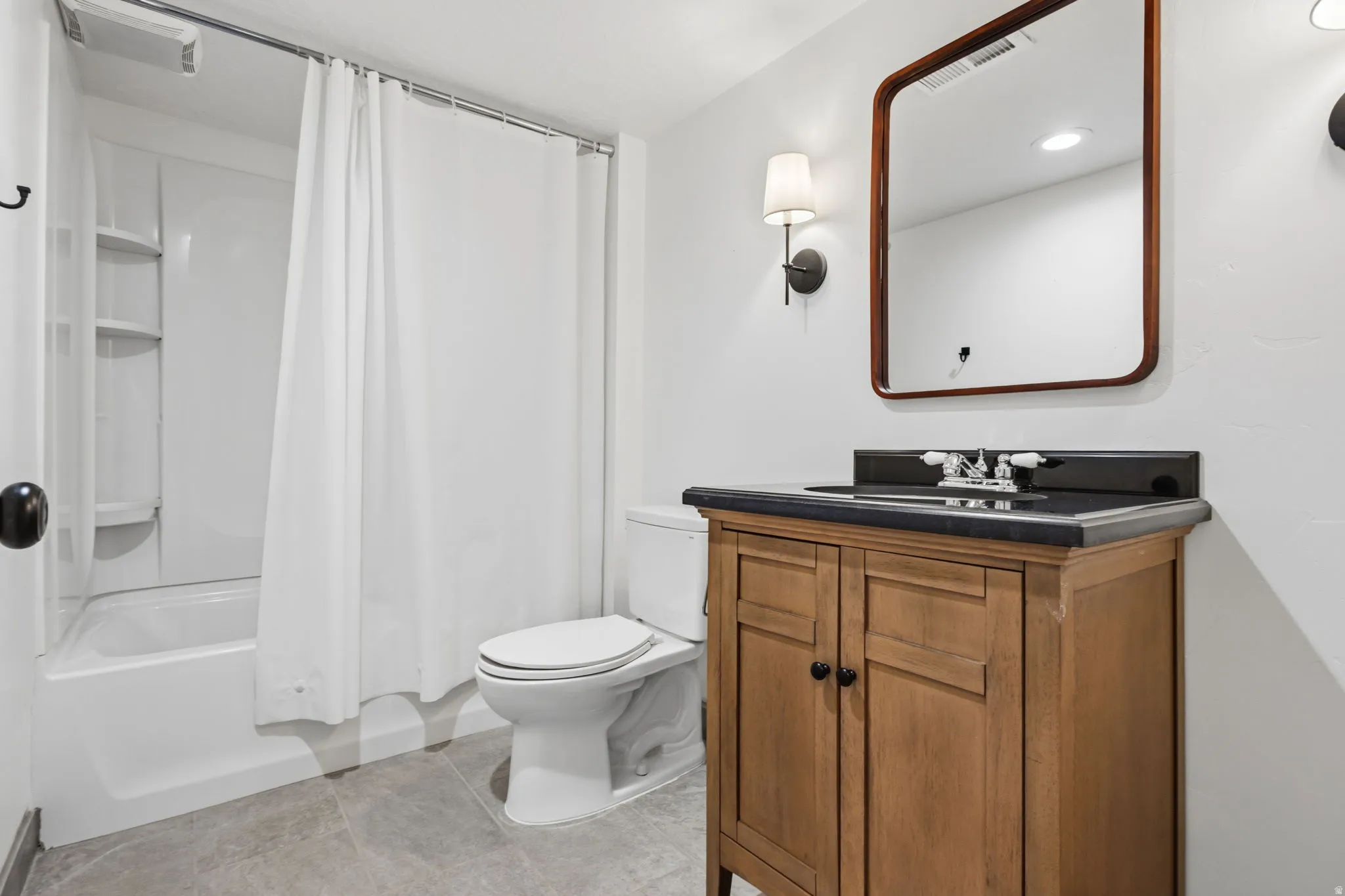 Bathroom featuring a wood-finish vanity with a dark countertop and undermount sink