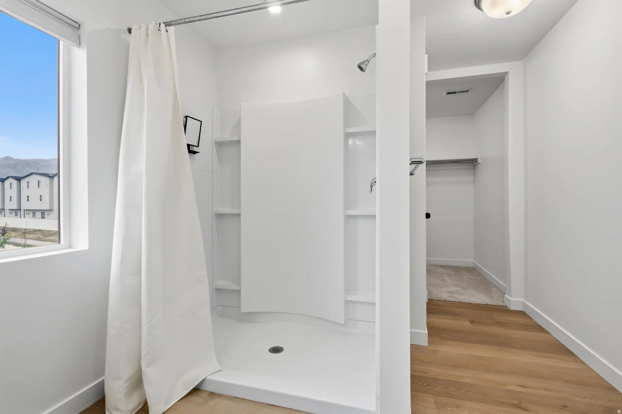 Shower with integrated shelving, window, and wood-finish flooring