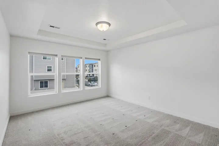 Bright interior space with a tray ceiling, recessed lighting, and a flush mount light fixture