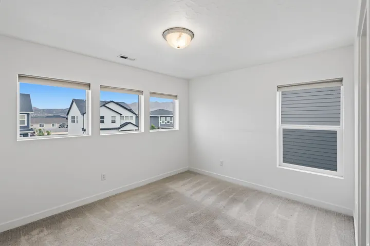 Carpeted room featuring multiple windows with roller shades, white walls, and a flush mount ceiling light
