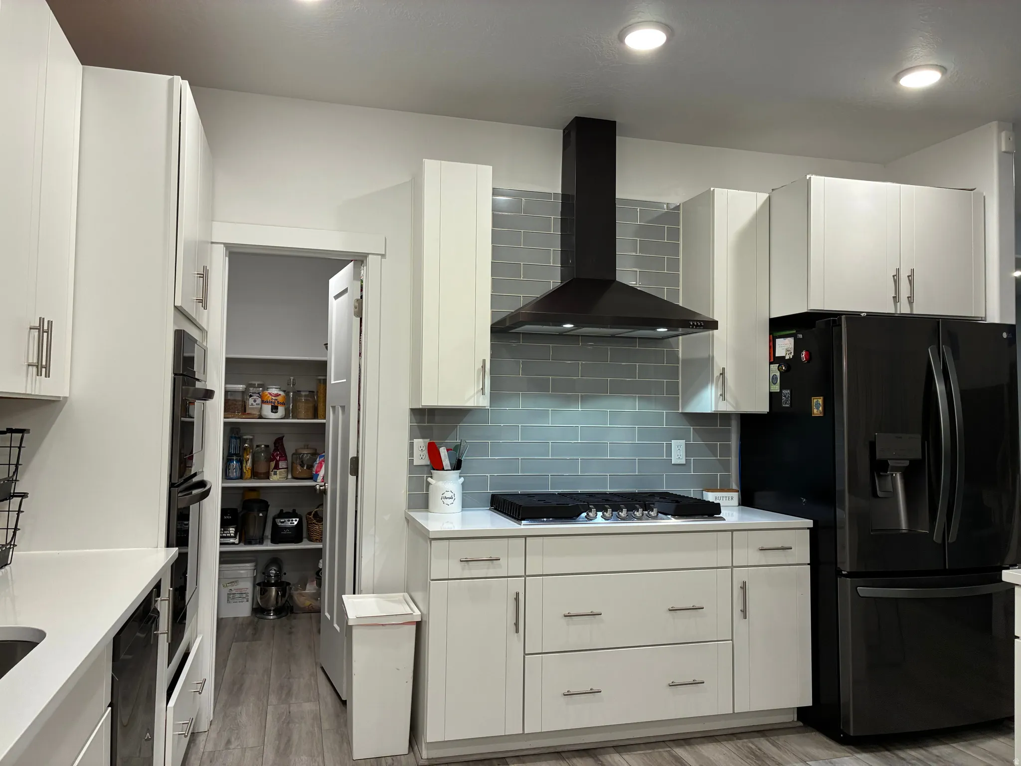 Modern kitchen featuring a black range hood and light grey subway tile backsplash
