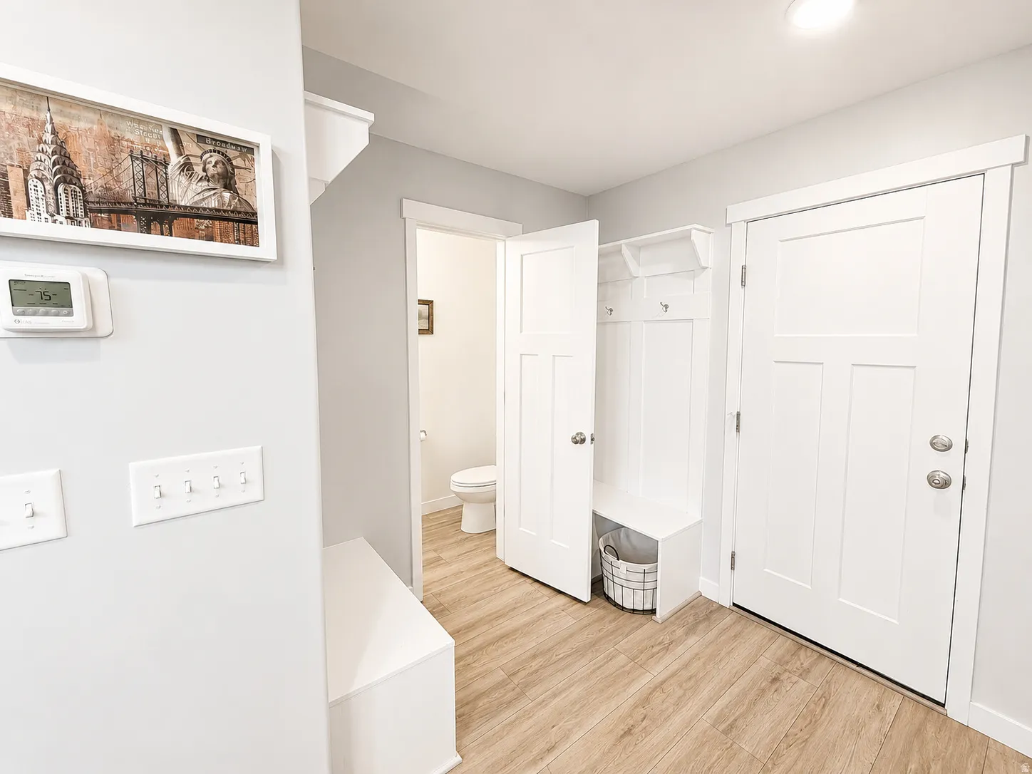 Wood-finish flooring, built-in storage bench with coat hooks, white panel doors, and recessed lighting
