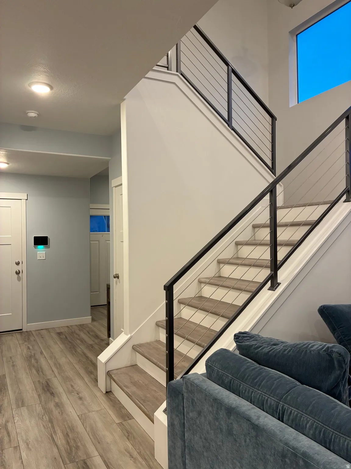 Staircase featuring contemporary metal cable railings and wood-finish treads