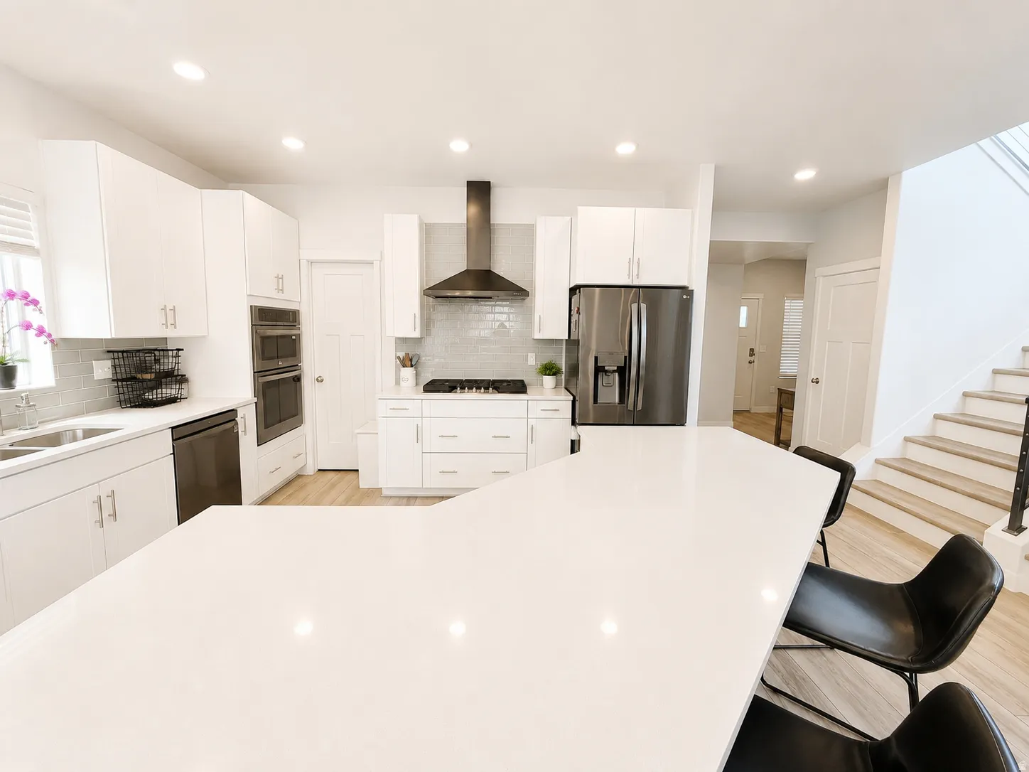Modern kitchen featuring white cabinetry, light countertops, and wood-finish flooring