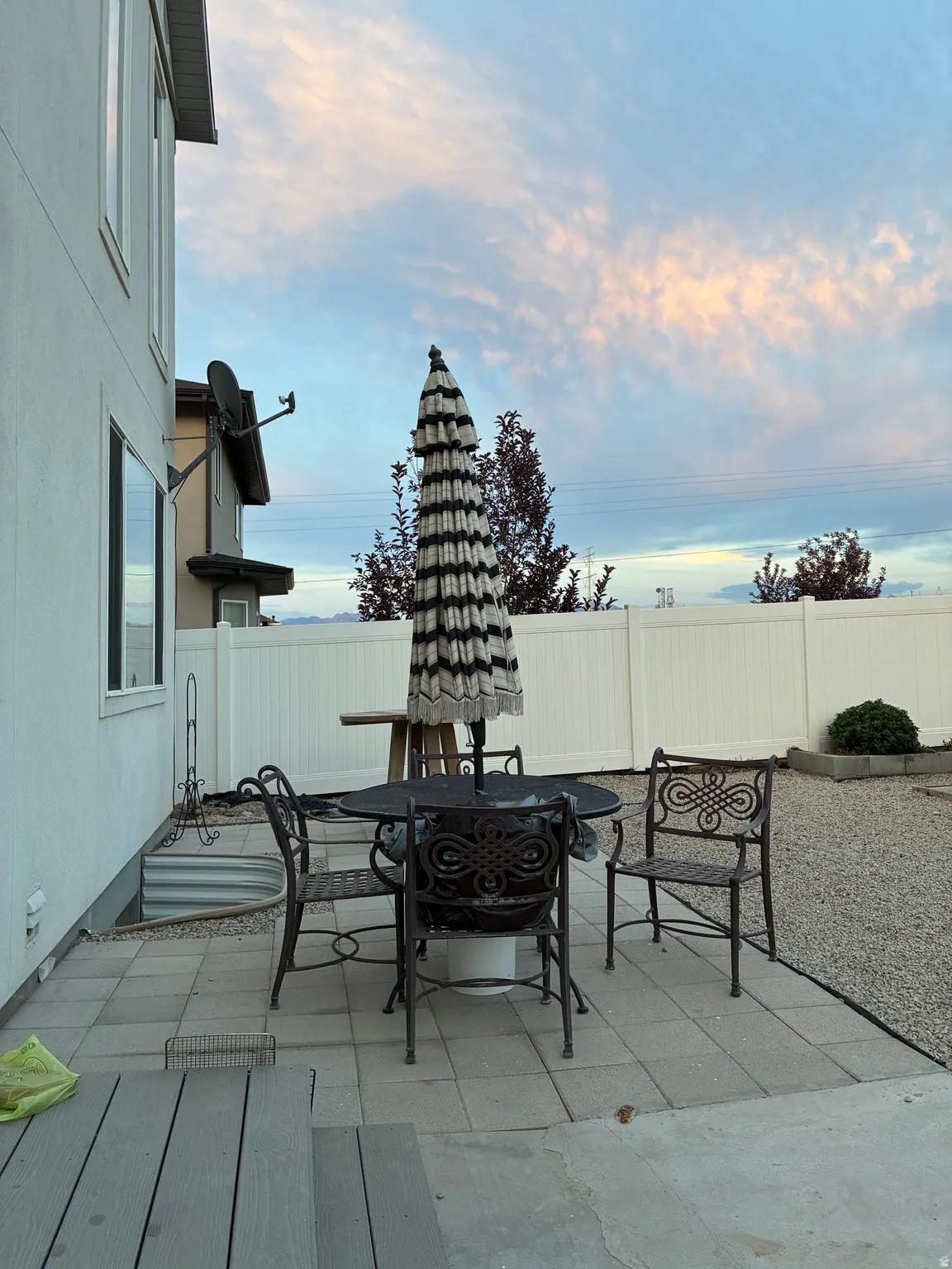 Outdoor patio featuring paver stones, a gravel area, and a white privacy fence