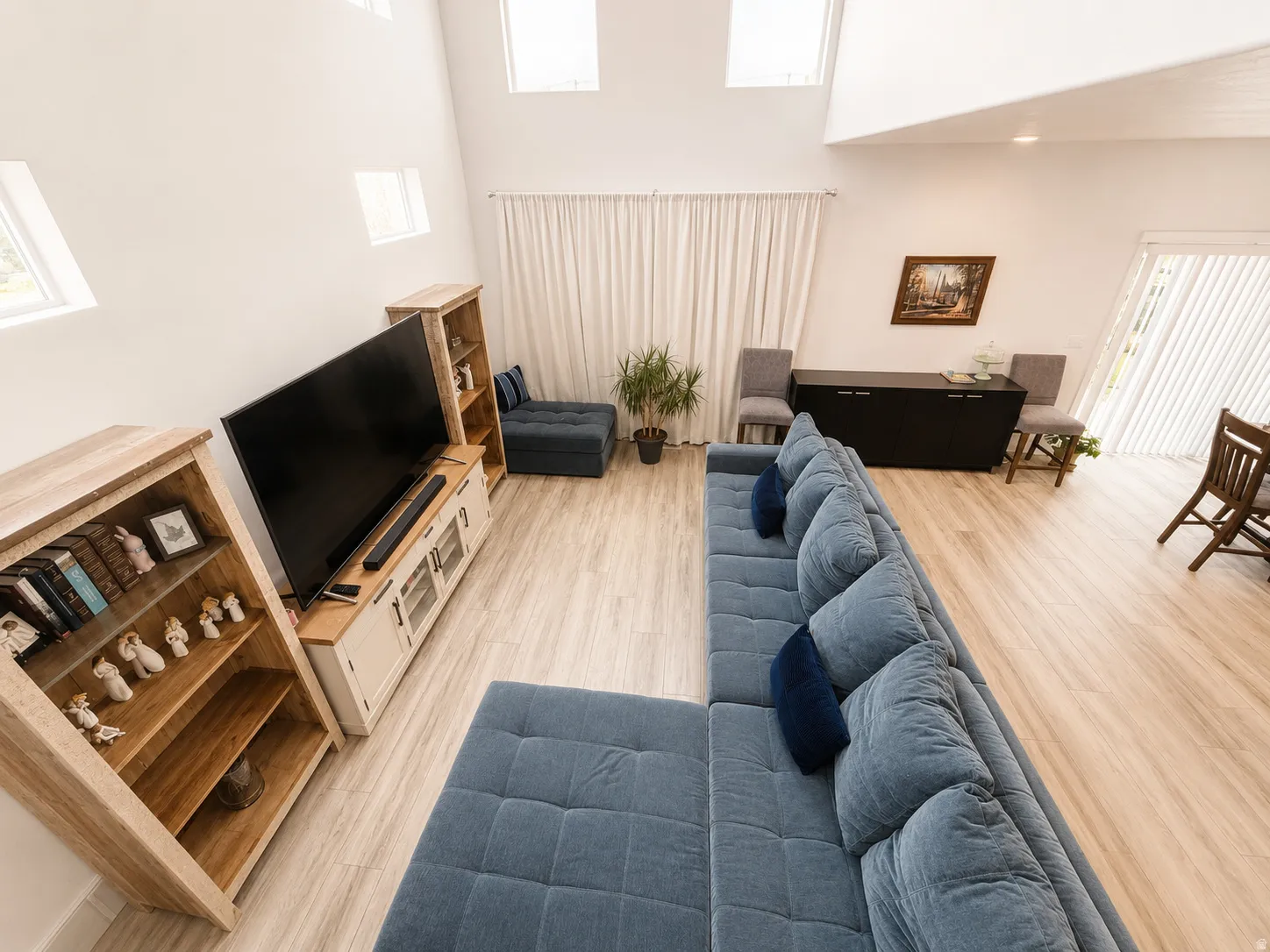 Vaulted ceilings with high-set windows, light wood-finish flooring, and white walls