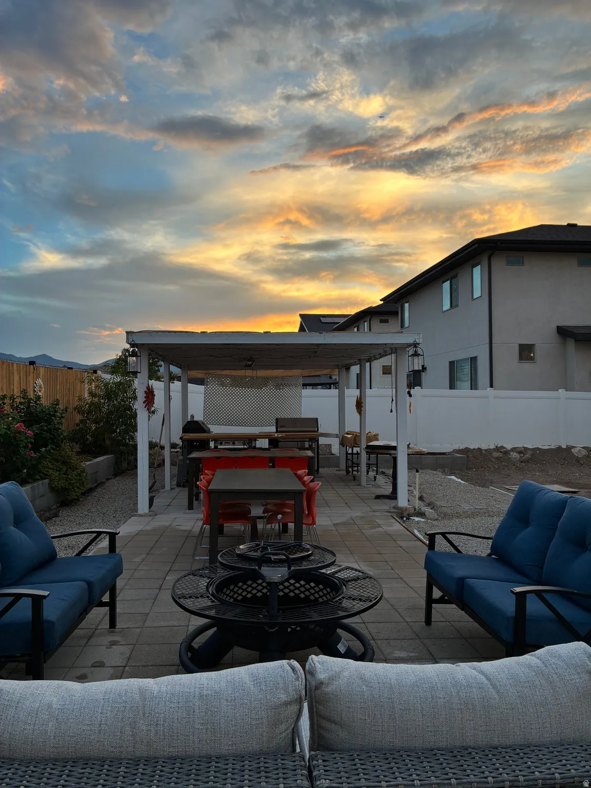 Paver patio featuring a white pergola structure, gravel landscaping, and a privacy fence