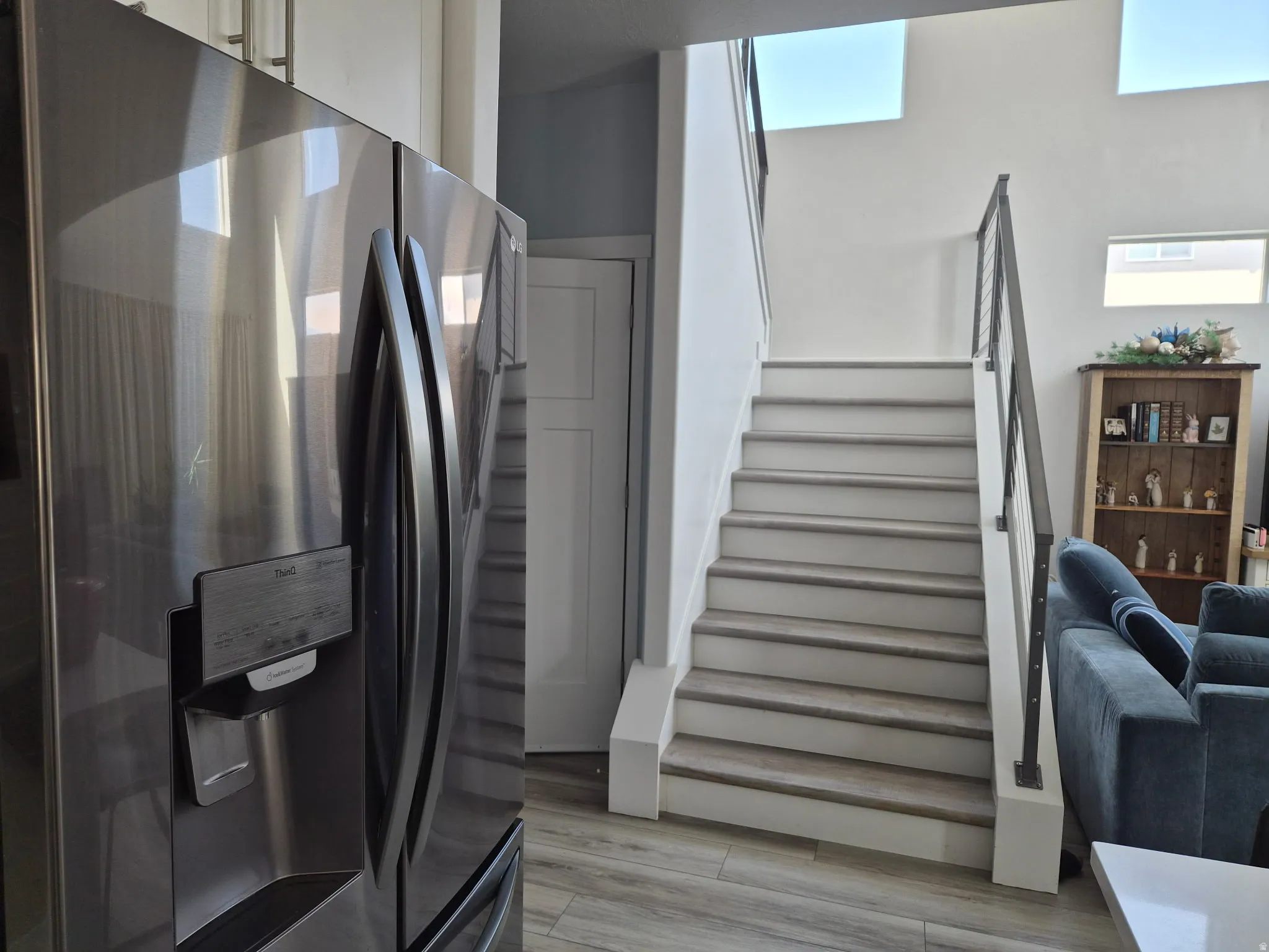 Interior staircase featuring wood-finish treads, white risers, and a contemporary metal railing