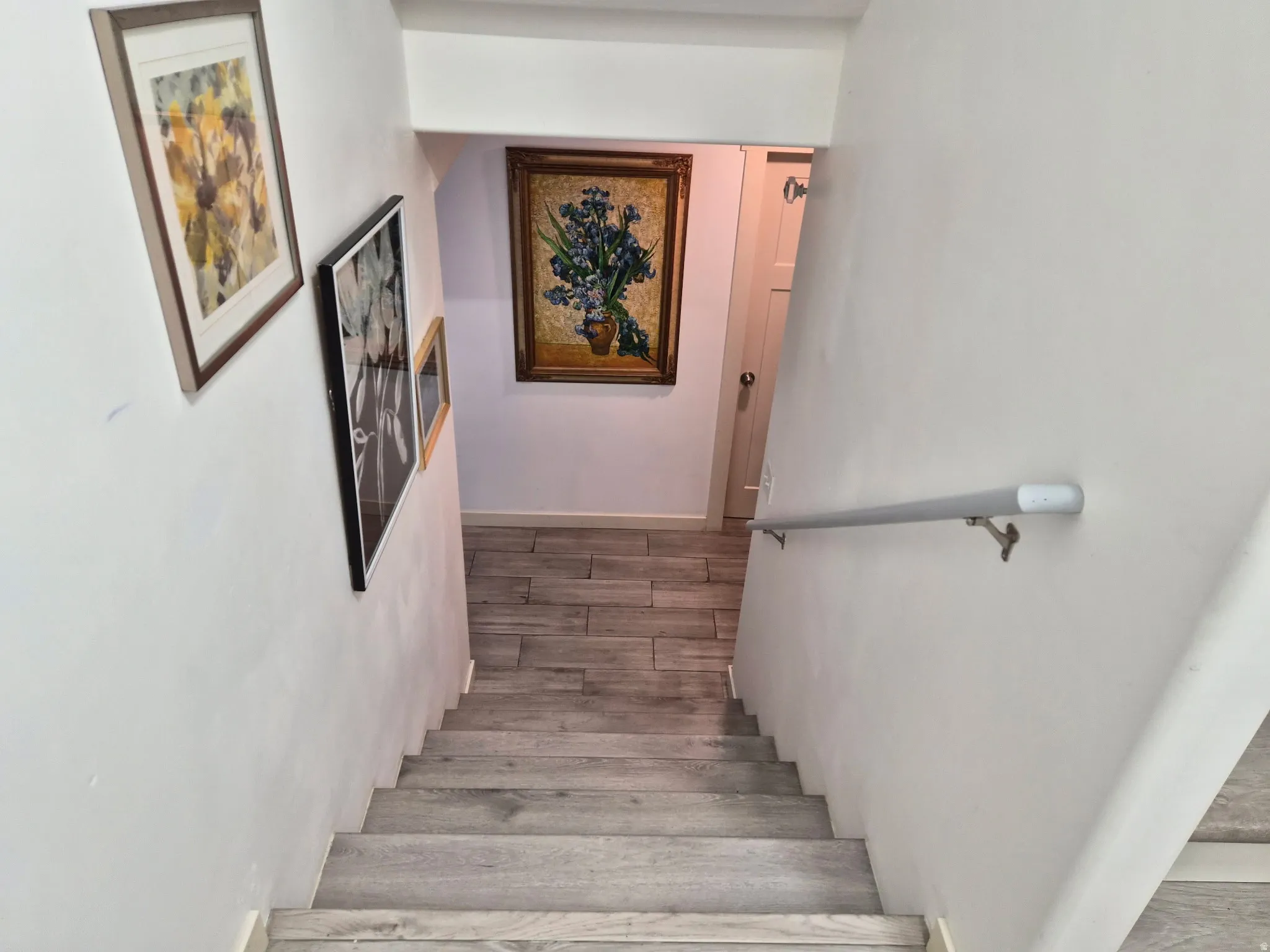 Stairwell with wood-finish treads and risers, complemented by a light-toned wall-mounted handrail