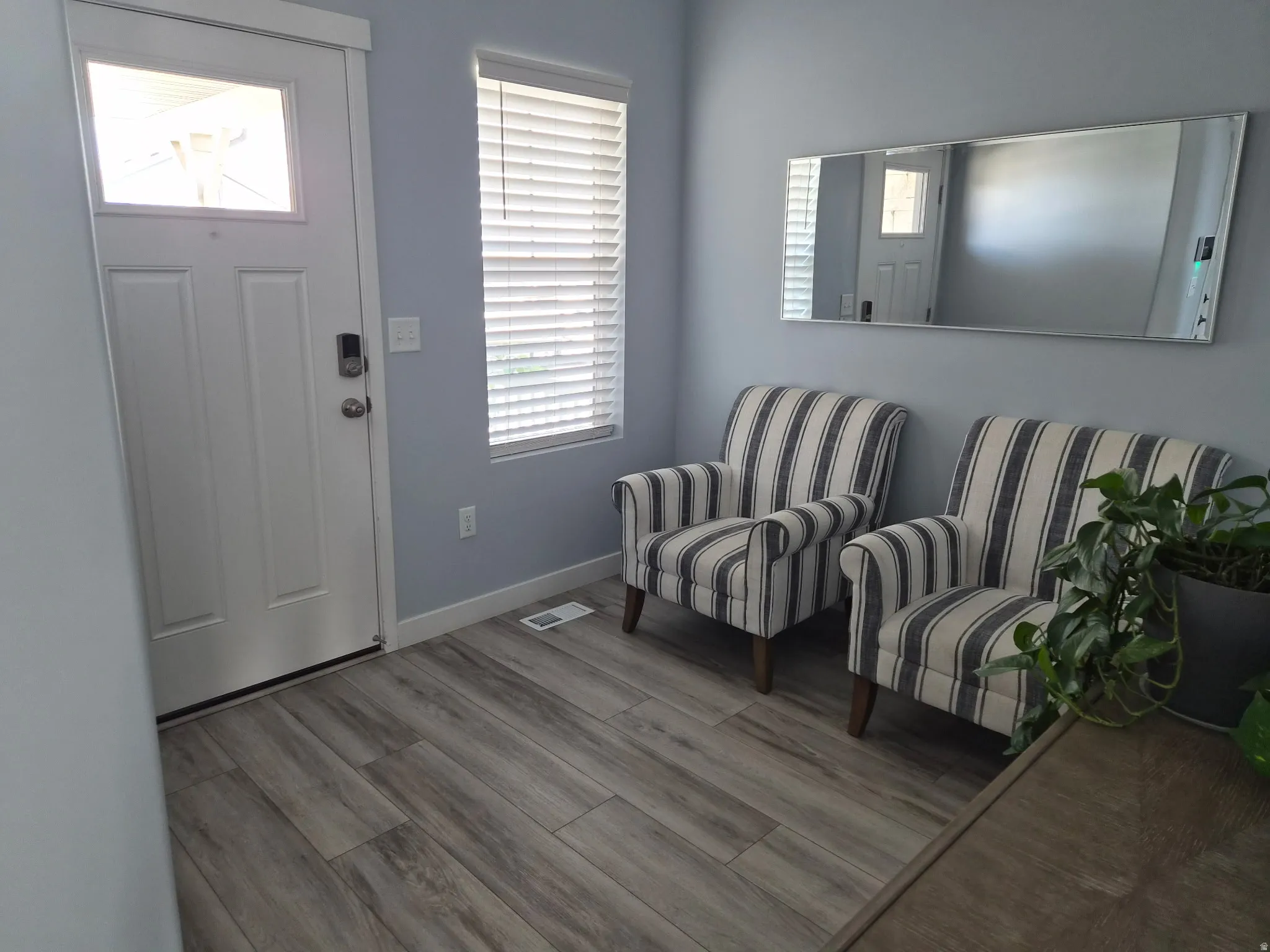 Entryway featuring wood-finish flooring, light blue wall paint, and a front door with an upper glass pane