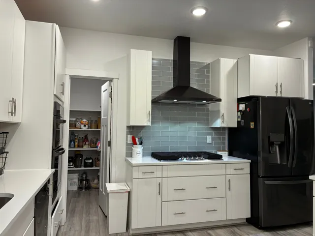 Modern kitchen featuring a black range hood and light grey subway tile backsplash