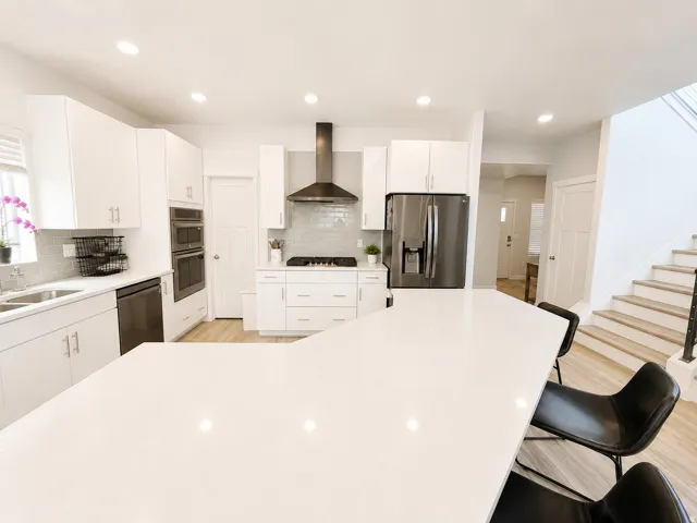 Modern kitchen featuring white cabinetry, light countertops, and wood-finish flooring