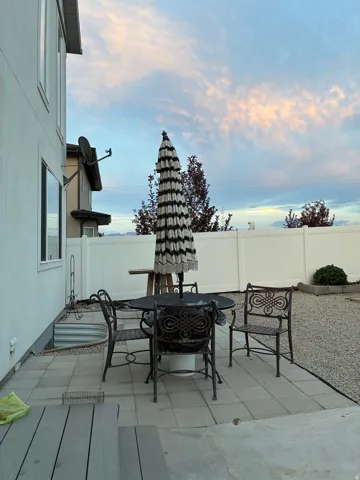 Outdoor patio featuring paver stones, a gravel area, and a white privacy fence