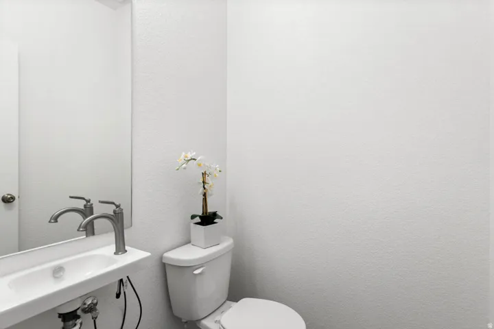 White textured walls highlight a contemporary wall-mounted sink with a brushed nickel faucet