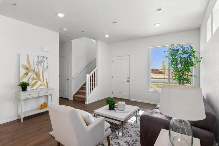 Open-concept living space with wood-finish flooring, recessed lighting, and a prominent window