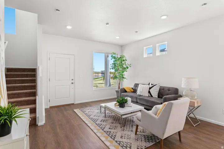 Open concept living space featuring wood-finish flooring, a contemporary white front door, and recessed lighting