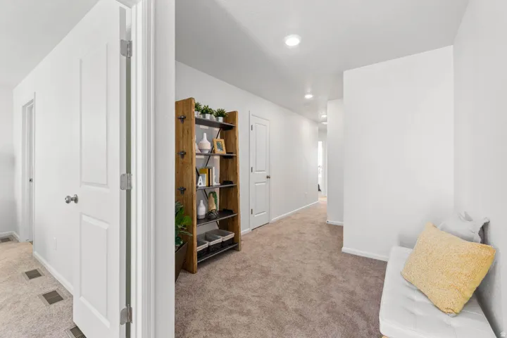 Carpeted hallway featuring recessed lighting and white paneled doors