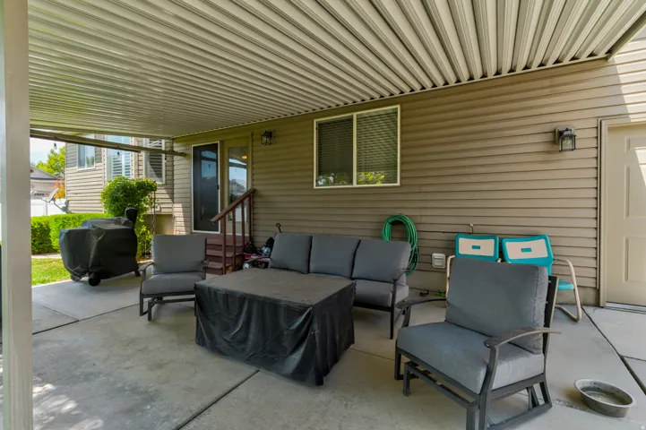 Covered patio featuring a ribbed ceiling, concrete flooring, exterior siding, and a rear entry door with adjacent window