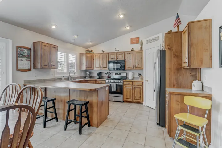 Spacious kitchen featuring light wood cabinetry, a central island with seating, stainless steel appliances, and recessed lighting