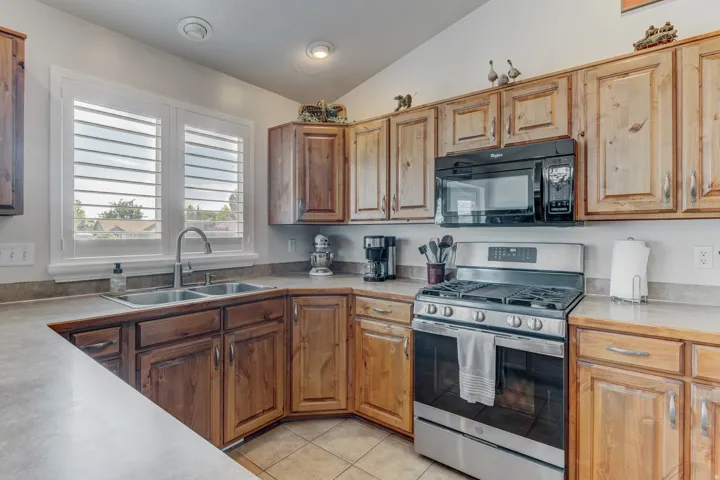 Kitchen featuring wood-finish cabinetry, solid surface countertops, a stainless steel gas range, and an over-range microwave
