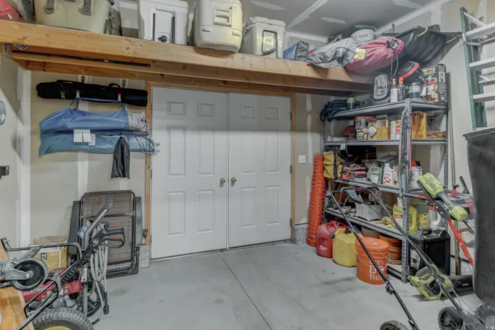 Storage in Garage featuring overhead wood-beam storage, and double panel doors to backyard