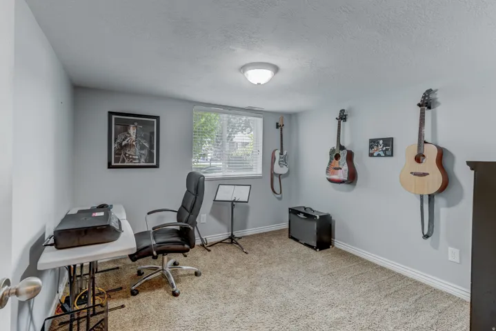 Carpeted room with light gray walls, a single window with blinds, and white baseboards