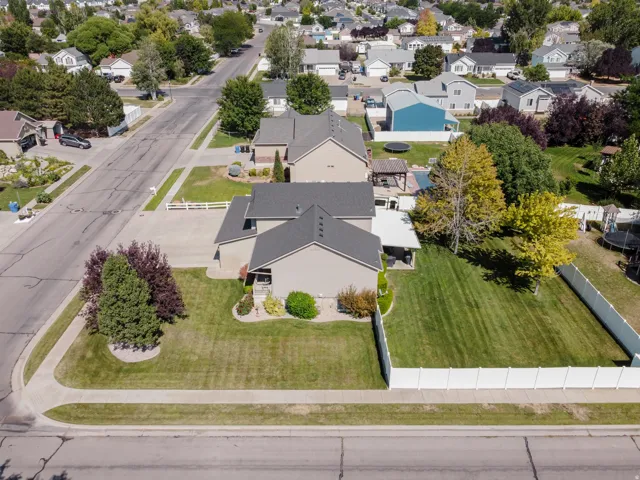 Spacious corner lot featuring a well-maintained lawn, mature trees, and white privacy fencing