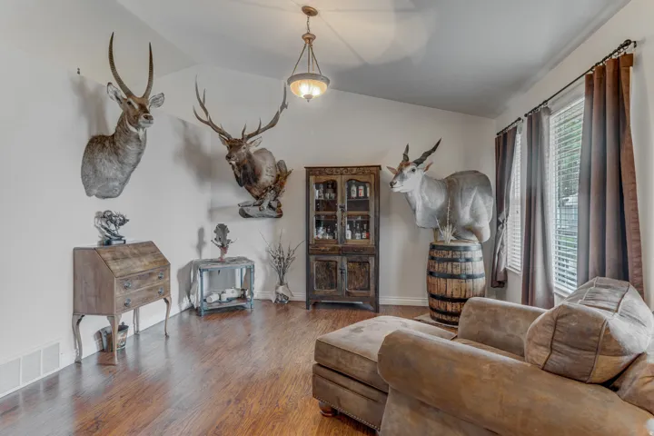Spacious room featuring vaulted ceilings, wood-finish flooring, and multiple windows with blinds