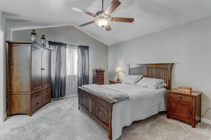 Vaulted ceiling with a ceiling fan, carpet flooring, window with blinds and drapes, and neutral wall tones