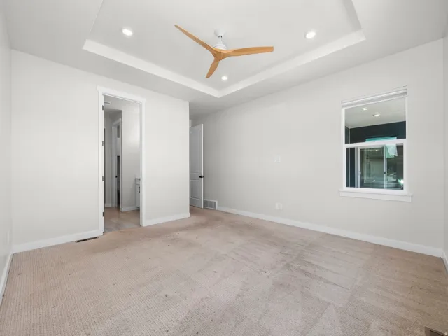 Spacious interior room featuring a tray ceiling with recessed lighting and a modern wood-blade ceiling fan