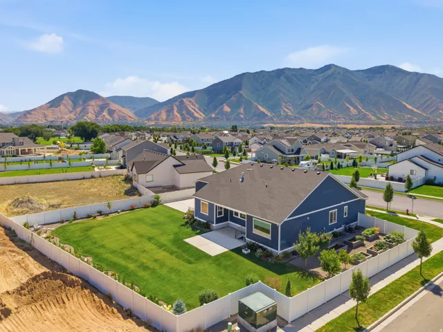 Blue exterior home with a dark shingle roof and a spacious green lawn