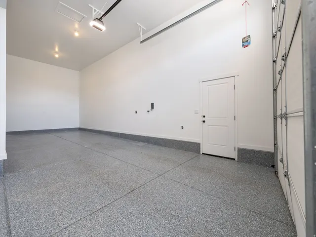 Spacious garage featuring a durable epoxy floor, white interior walls, and an interior access door