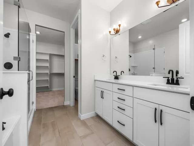 Bathroom featuring a double vanity with white cabinetry, matte black hardware, and a large mirror