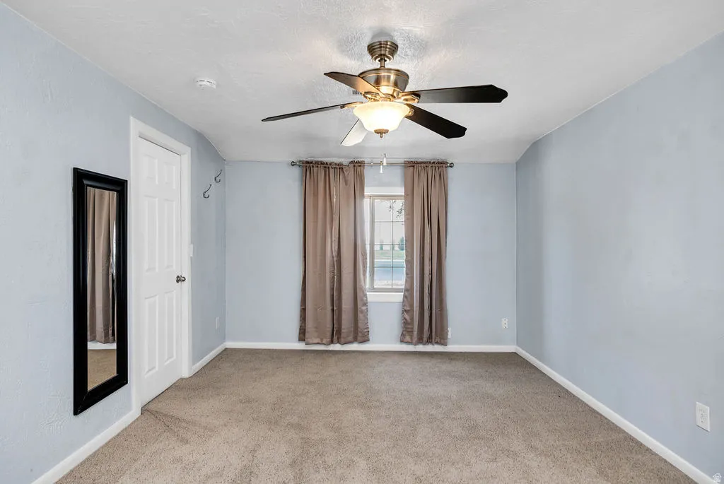 Spacious room featuring neutral carpeting, light blue walls, and a white paneled door