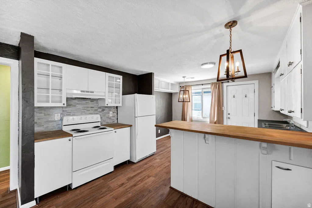 Kitchen featuring wood-finish flooring, white cabinetry, a tile backsplash, and wood countertops
