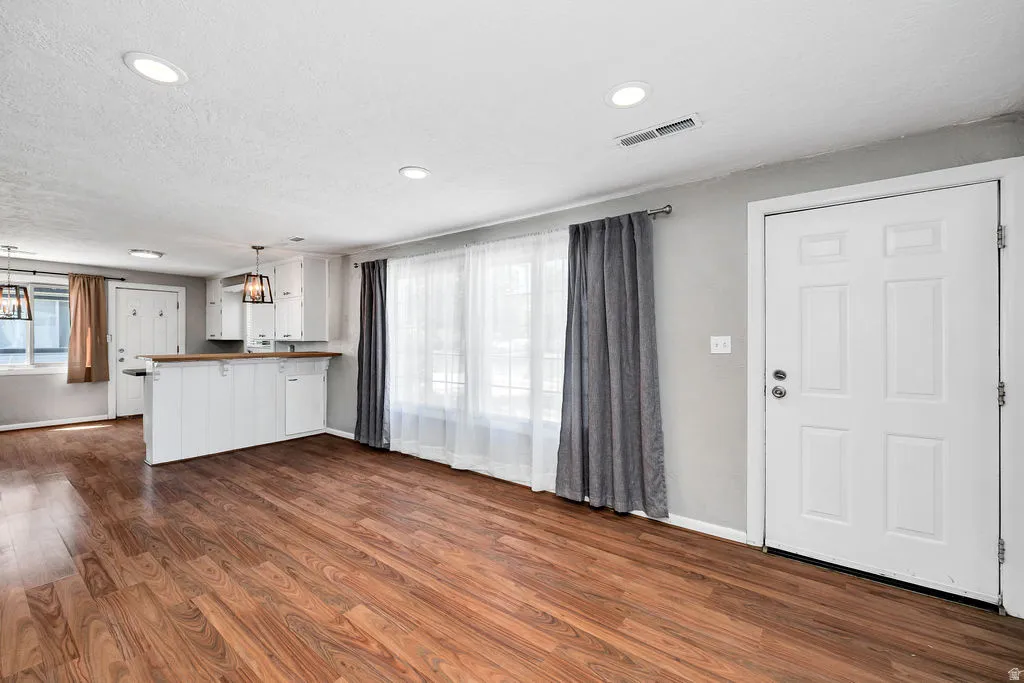 Open-concept living area featuring wood-finish flooring, recessed lighting, and a white six-panel entry door