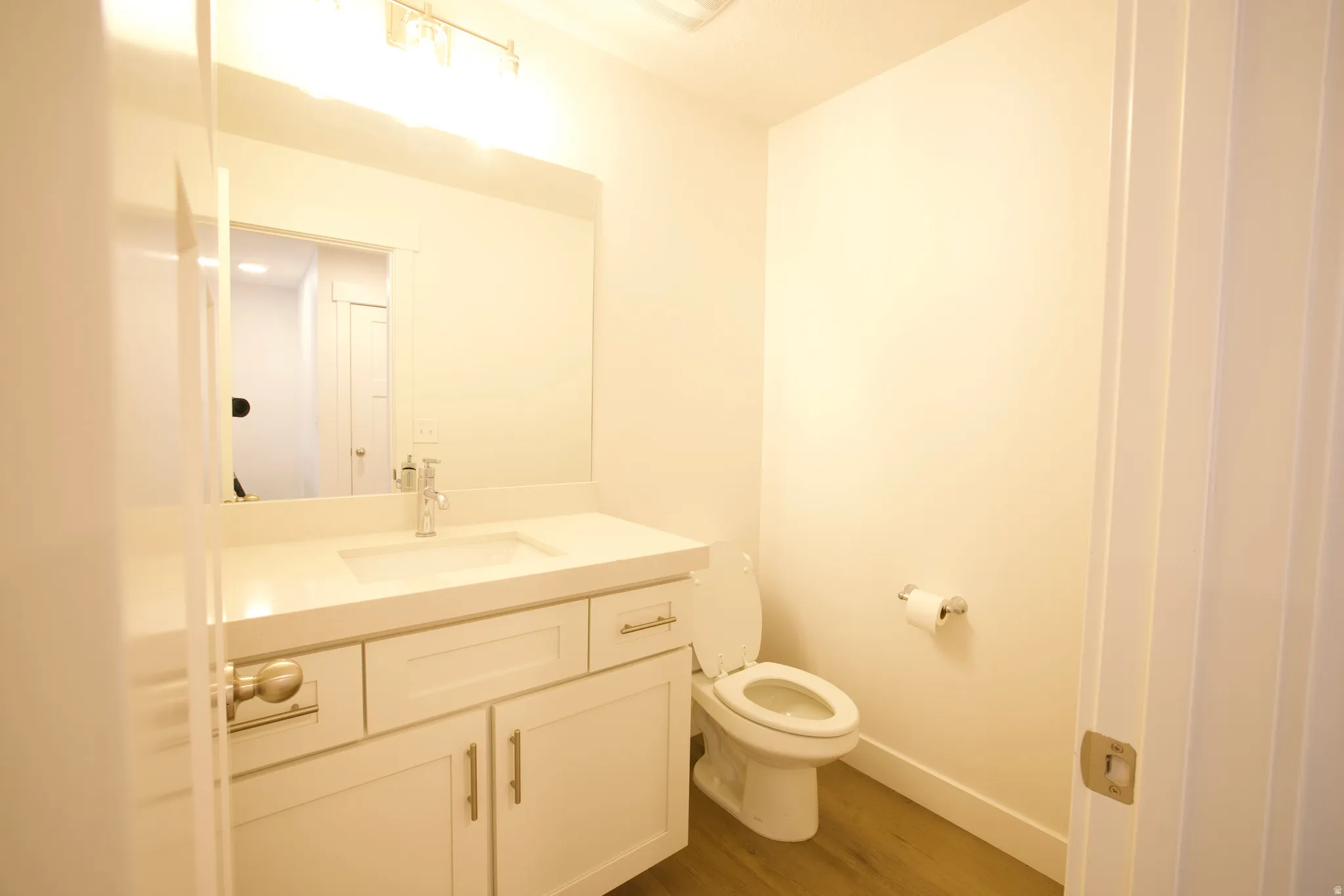 White vanity with shaker-style cabinetry, a built-in rectangular sink, and a chrome faucet