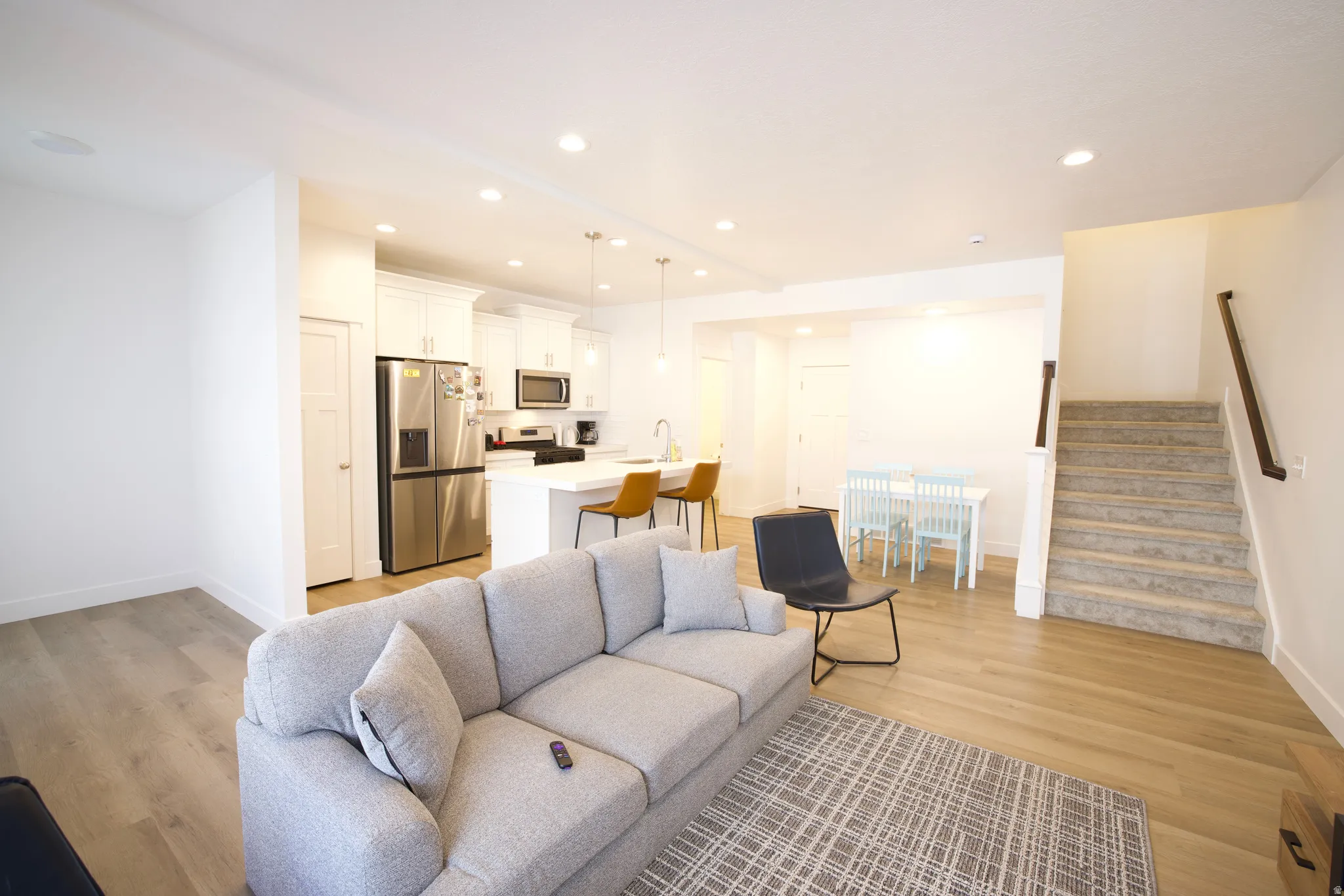 Open-concept living space featuring a modern kitchen with stainless steel appliances, a kitchen island with pendant lighting, and recessed ceiling lights throughout