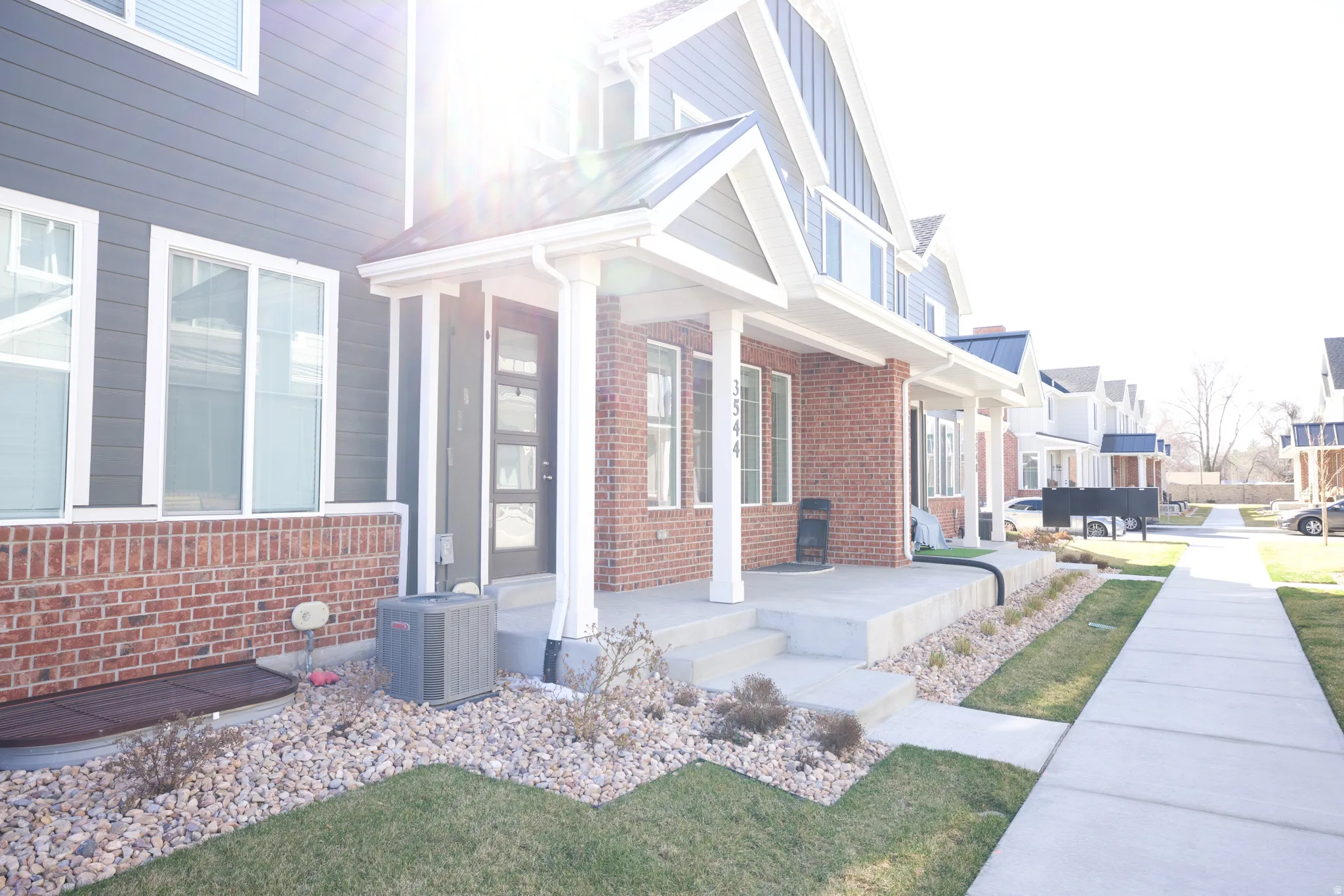 Contemporary townhome exterior featuring gray horizontal siding and brick accents