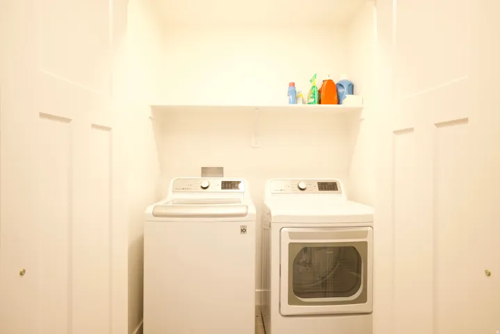 Dedicated laundry area featuring a built-in shelf for storage and a white paneled closet door
