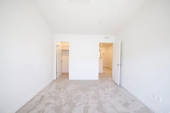 Light-filled room featuring neutral-toned carpeting, crisp white walls, white trim, and two doorways
