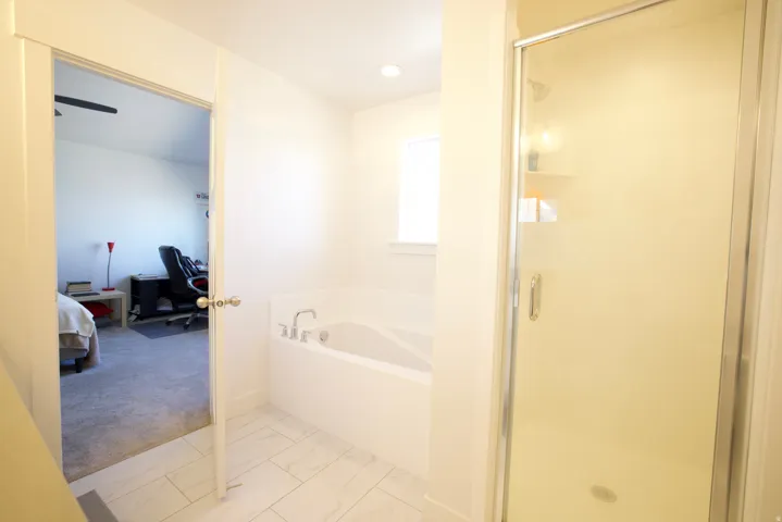 Bathroom featuring a built-in soaking tub, a glass-enclosed shower, and large format tile flooring