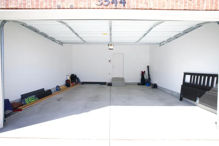 Spacious two-car garage with a concrete floor, bright white walls, and an overhead garage door