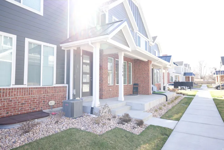 Contemporary townhome exterior featuring gray horizontal siding and brick accents